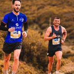 Dynamic image of two men trail running through an outdoor natural setting, showcasing energy and fitness.